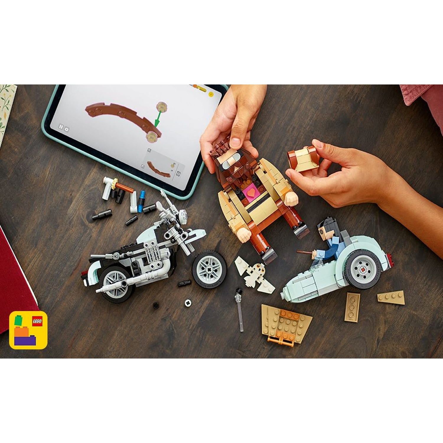 Set Lego con moto, auto e figura con istruzioni. Mani che assemblano i personaggi su un tavolo di legno. Logo Lego nell'angolo.