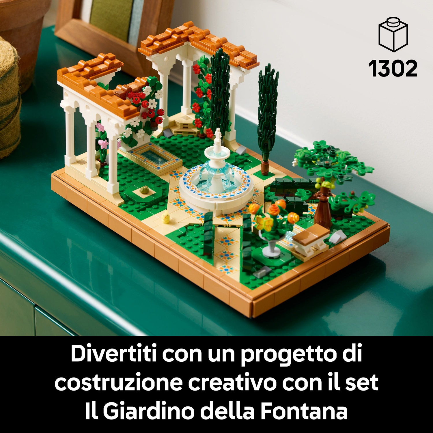 Un set Lego di un giardino con fontana. Presenta una fontana, un gazebo, alberi e fiori su una superficie verde.