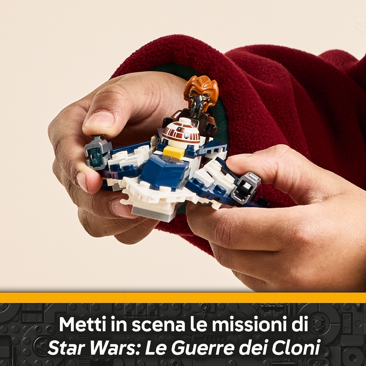 Mani che tengono una nave Lego di Star Wars con una figura dentro. La nave è blu, bianca e grigia. Lo sfondo è una giacca rossa.