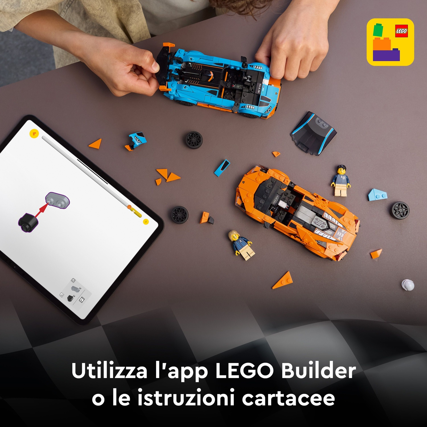 Mani che assemblano auto Lego, blu e arancioni. Un tablet mostra le istruzioni. Figure e pezzi Lego sparsi su un tavolo.