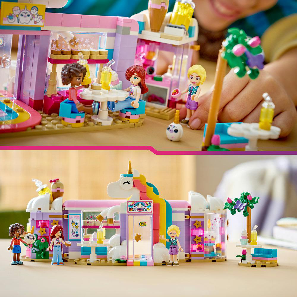 Ein Lego-Set mit einem Café im Einhorn-Design. Figuren sitzen an Tischen, eine Kinderhand ist sichtbar.