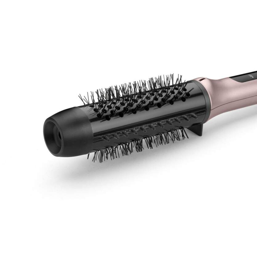Primer plano de un cepillo para el cabello. Tiene cerdas negras y un mango dorado rosado. El fondo es blanco.