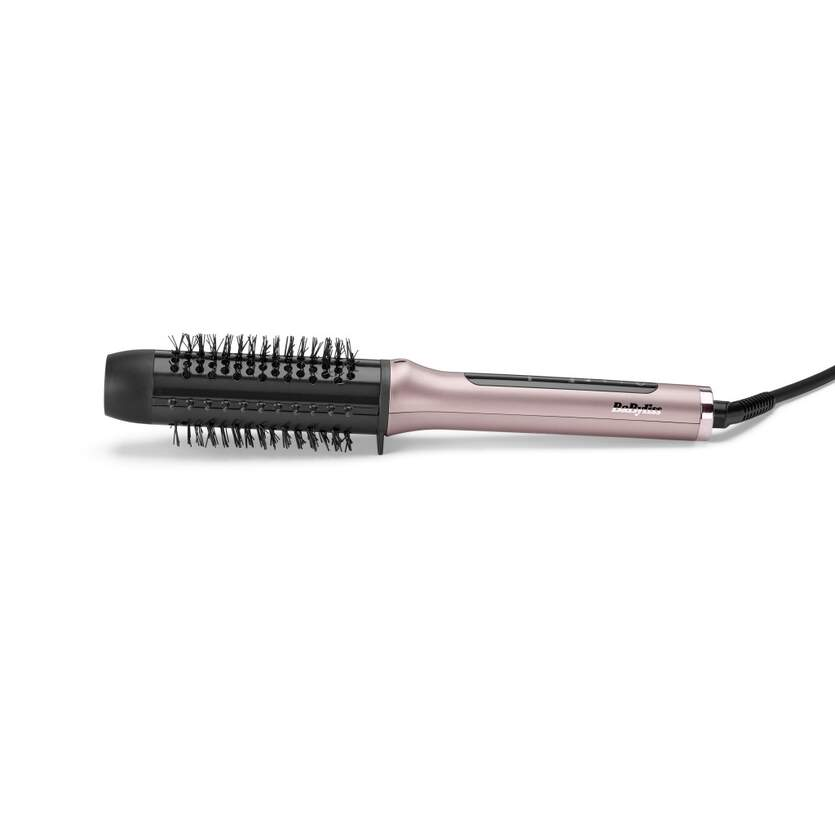 Un cepillo para peinar el cabello rosa dorado y negro está sobre una superficie blanca. Tiene cerdas y un mango con cable.