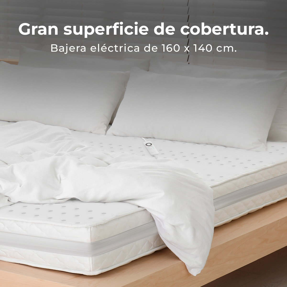 Una cama con ropa de cama blanca, incluyendo almohadas y edredón. Se ve una manta eléctrica. El marco de la cama es de madera.
