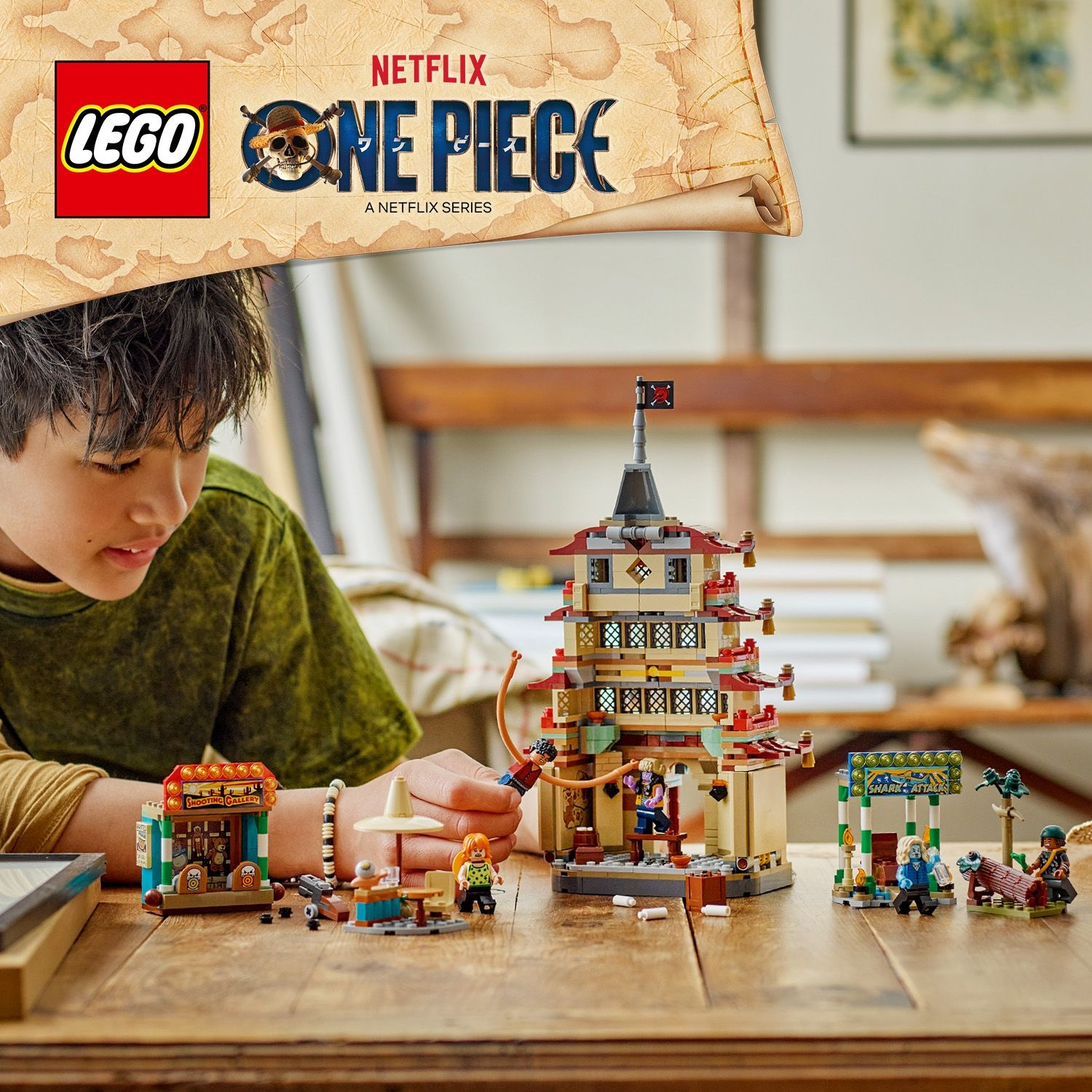 Un ragazzo guarda un set Lego One Piece. Il set include una pagoda e varie minifigure su un tavolo di legno. Il logo Netflix è visibile.