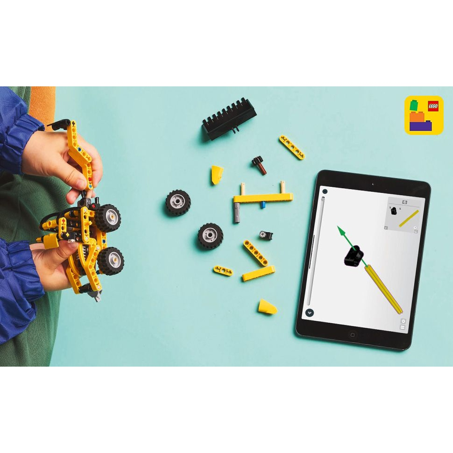 Un bambino tiene in mano una struttura Lego gialla e nera. Parti e un tablet con le istruzioni sono su una superficie blu. Logo Lego nell'angolo.
