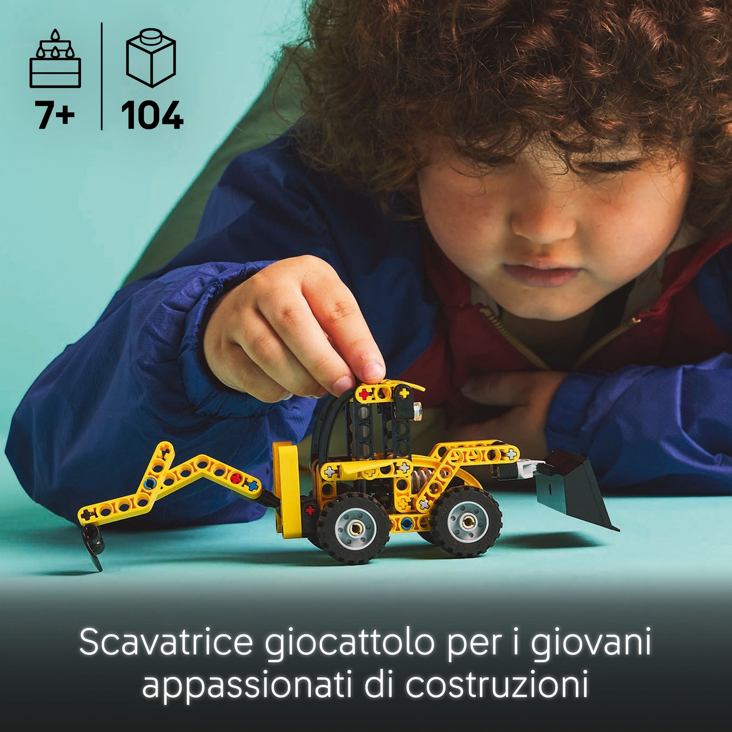 Un bambino gioca con un giocattolo da costruzione giallo e nero. Il giocattolo è una piccola scavatrice. Lo sfondo è verde acqua.
