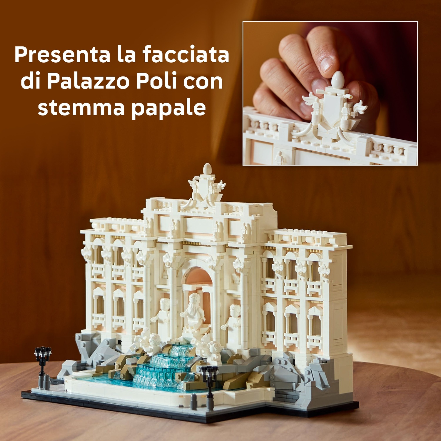 Un modello Lego di un edificio con una fontana. È bianco e ha un elemento acquatico blu. Una mano mette una parte sopra.