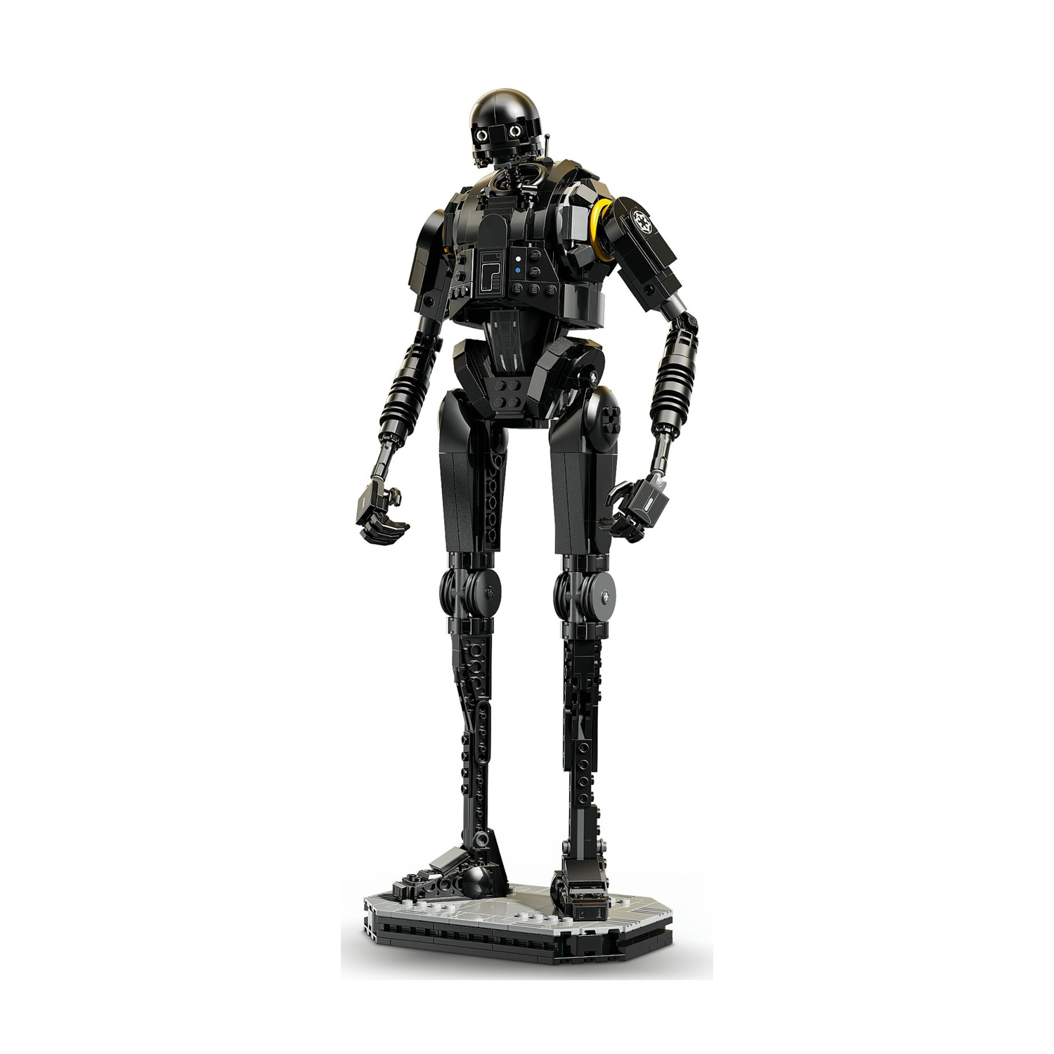 Un droide K-2SO Lego nero è in piedi su una base grigia contro uno sfondo bianco. Ha una testa arrotondata e arti meccanici.