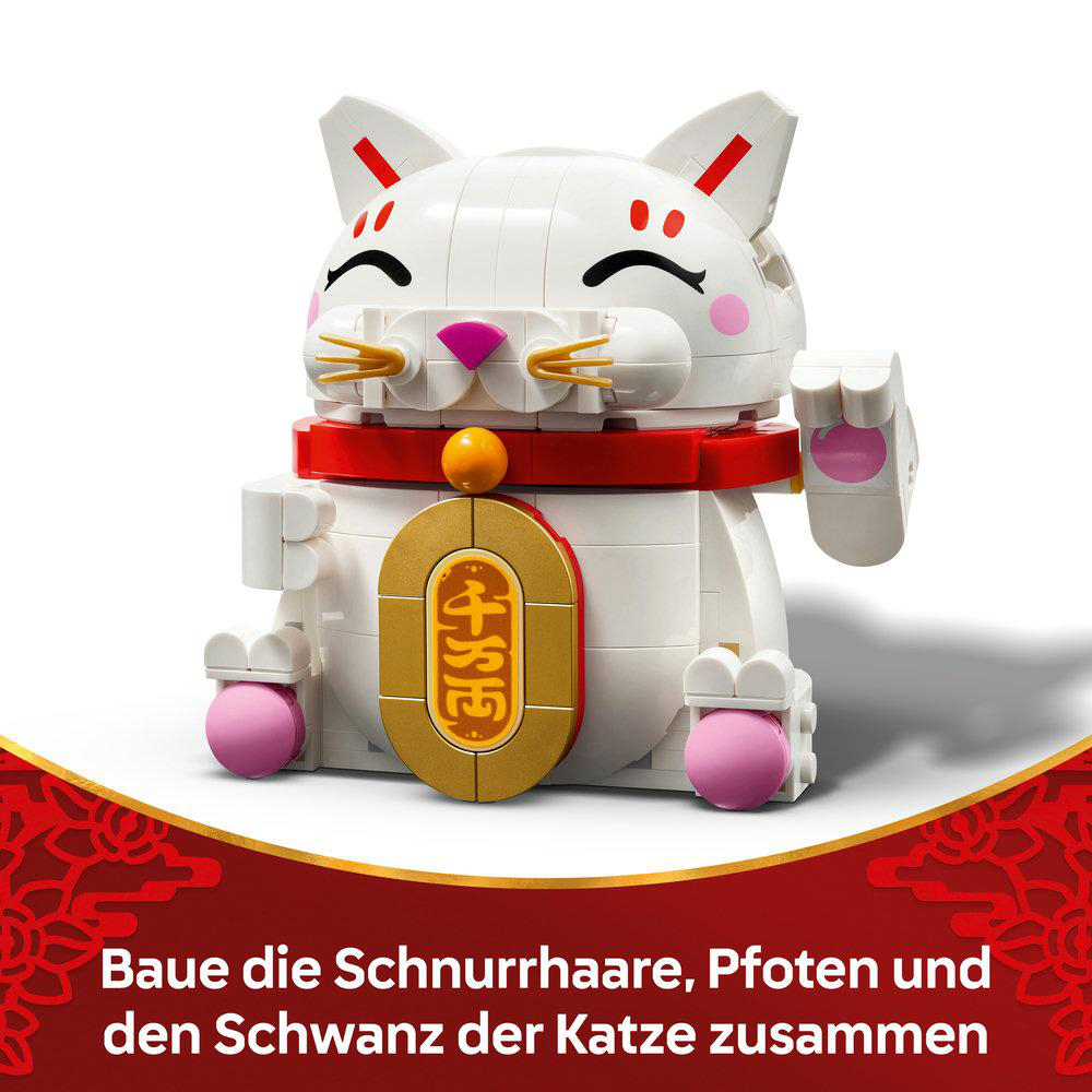 Eine weiße Lego-Katze mit rotem Kragen und goldenem Anhänger. Pinke Akzente auf Pfoten und Wangen. Text unten auf Deutsch.