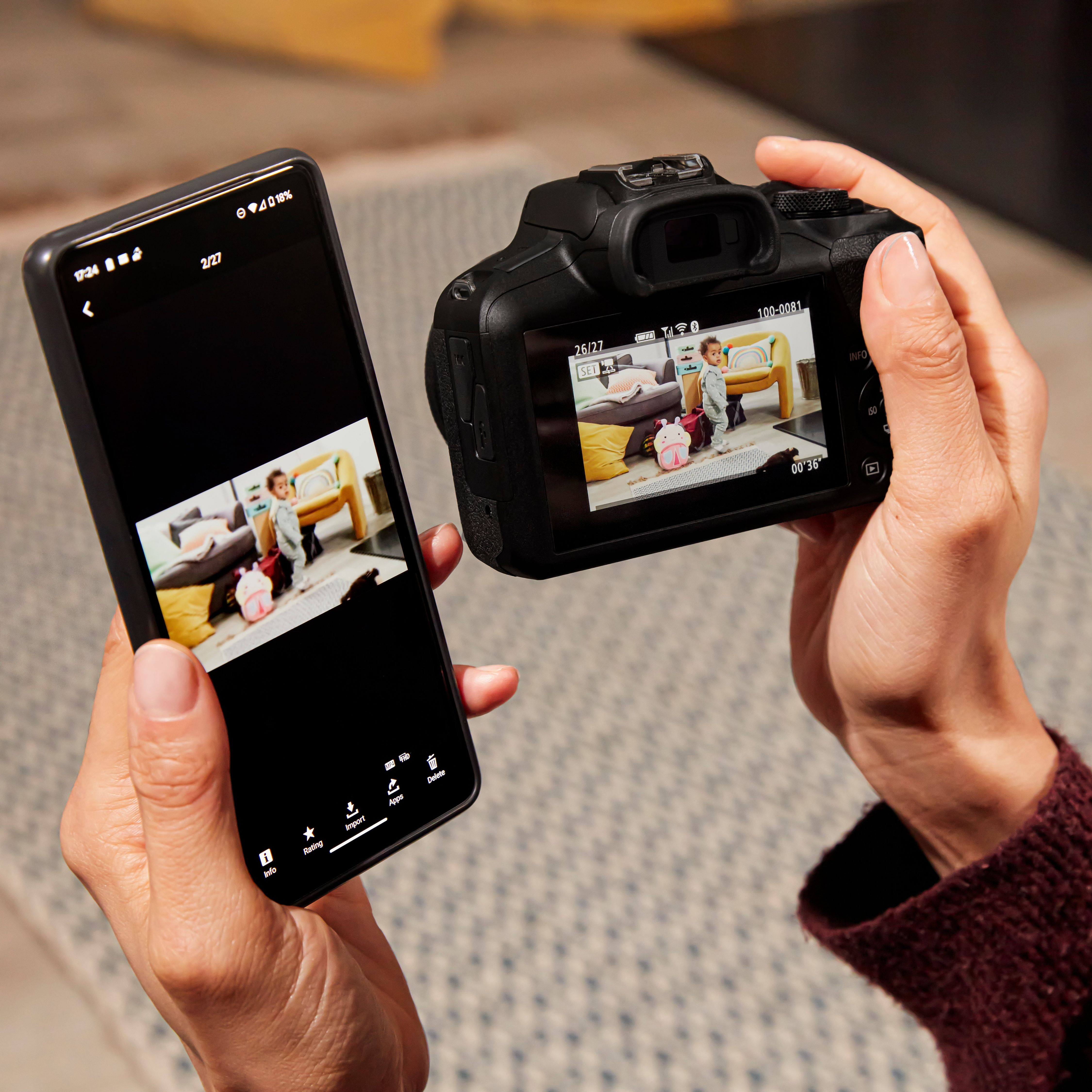Des mains tiennent un téléphone et un appareil photo, affichant un enfant dans une pièce. Le téléphone montre une photo et l'appareil photo aussi.