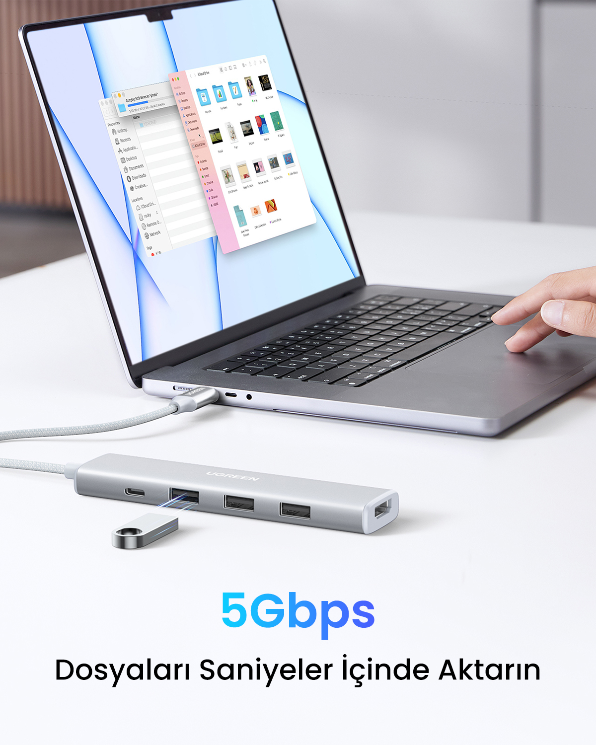 Bir elin işaret ettiği, gümüş bir USB hub'ına bağlı bir dizüstü bilgisayar. Ekranda "Copying" kelimesi ile dosya aktarımı gösteriliyor.