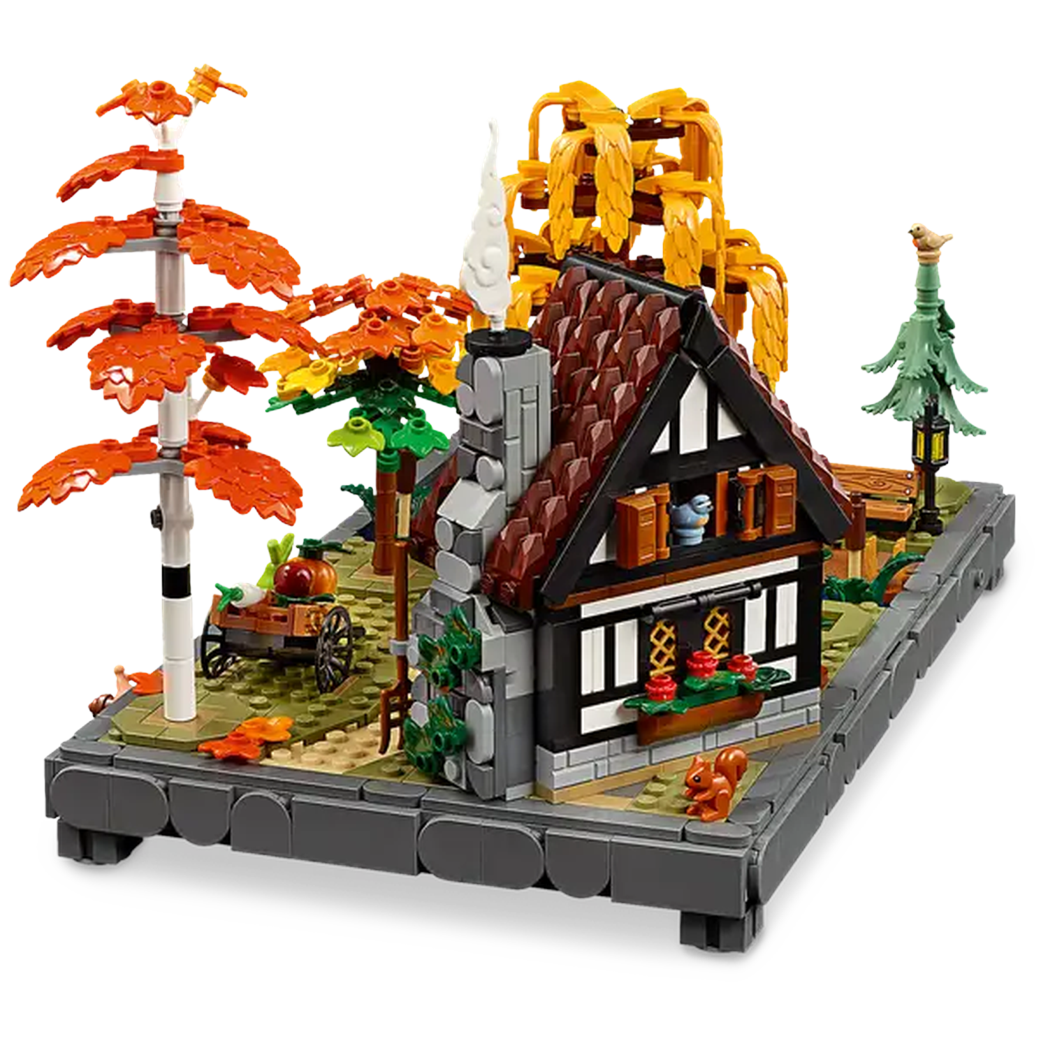 A Lego model of a cottage with trees. The cottage has a chimney, a red roof, and a black and white facade.