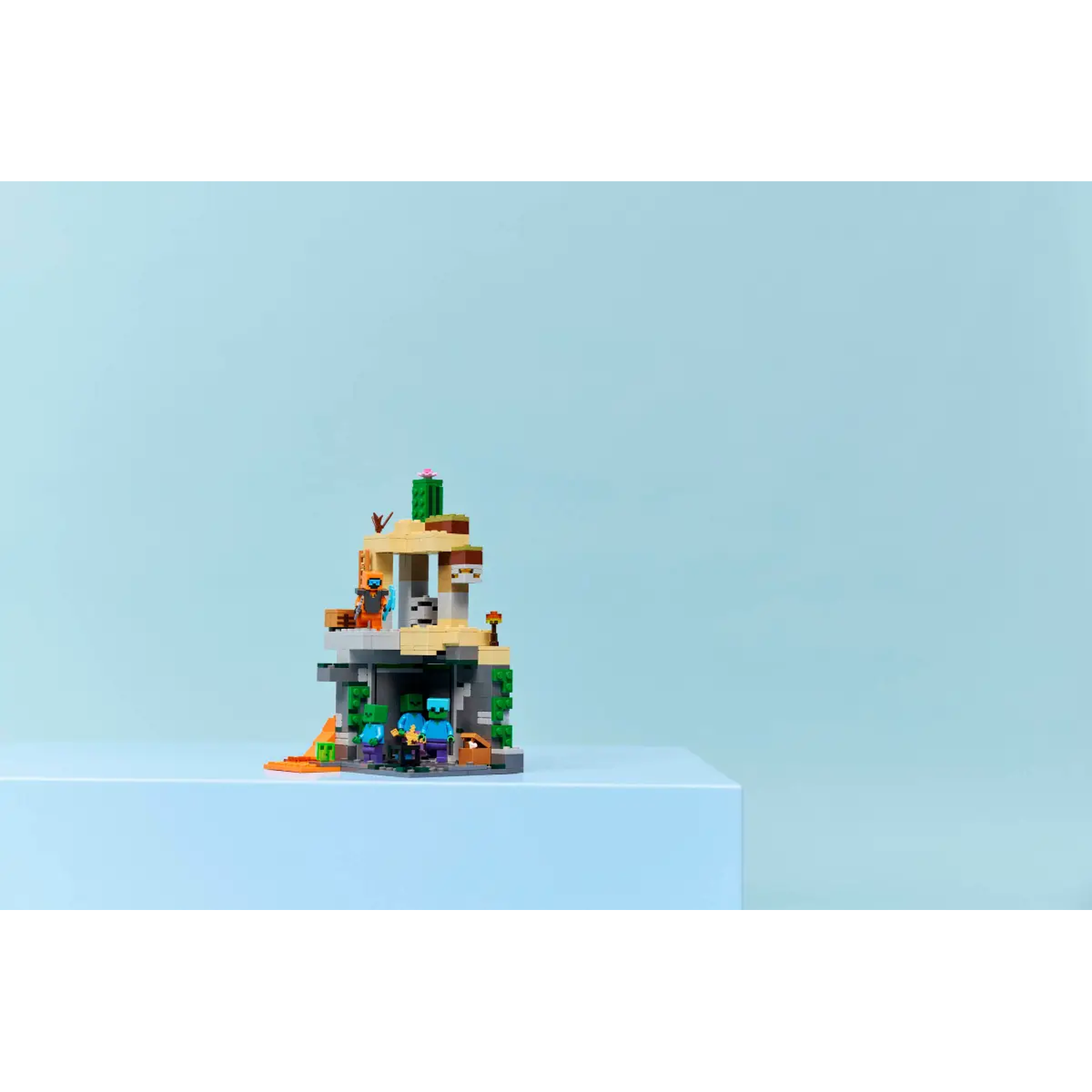 Een Lego Minecraft-scène. Een structuur met personages en details op een blauw oppervlak, tegen een lichtblauwe achtergrond.