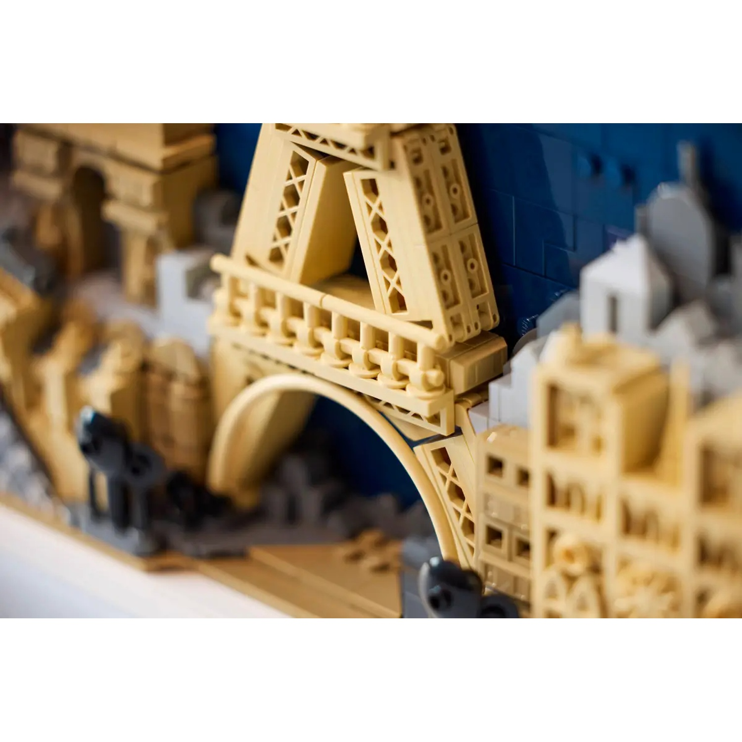 A Lego model of Paris, featuring the Eiffel Tower, bridge, and buildings. Beige and blue blocks create the scene.