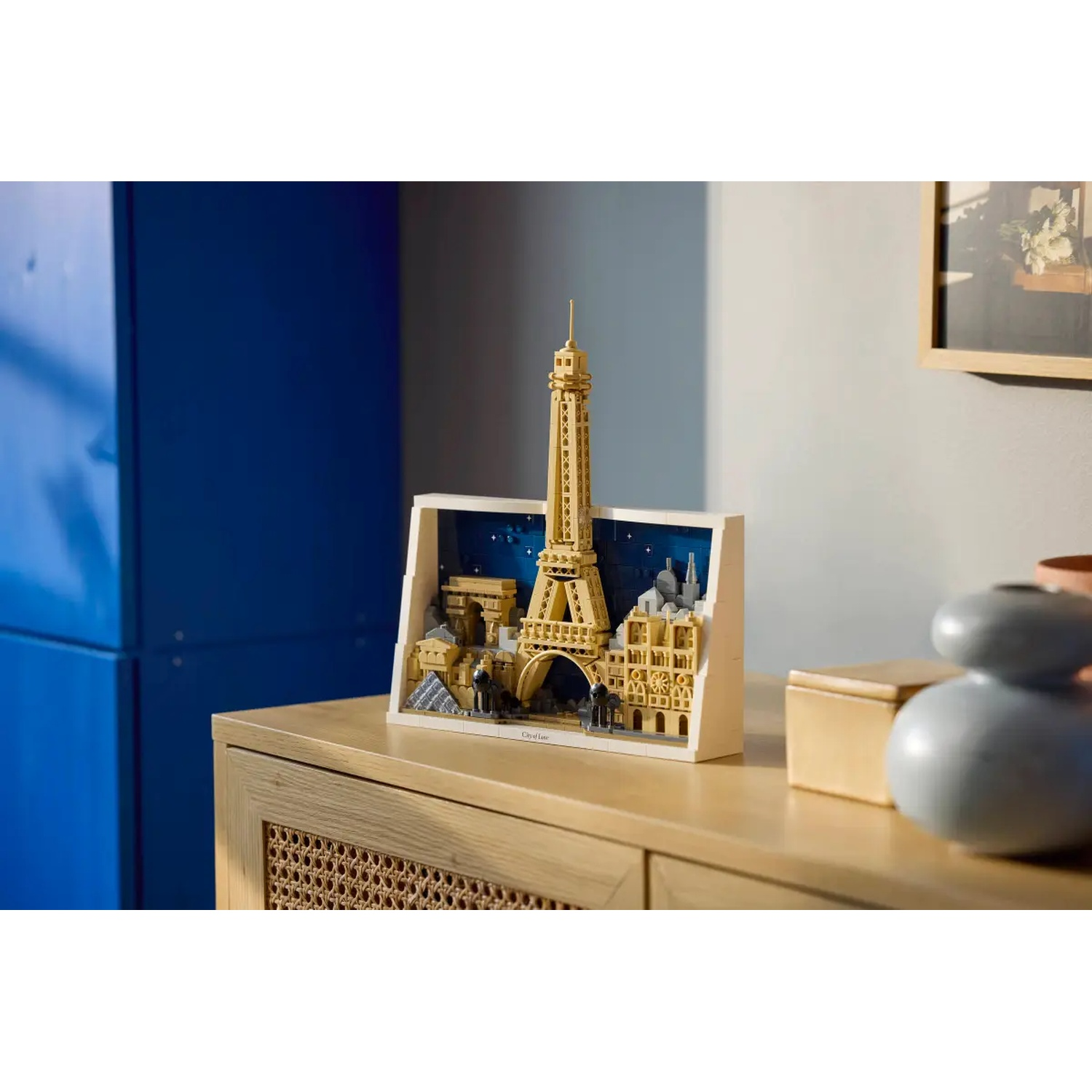 A Lego model of Paris, featuring the Eiffel Tower, displayed on a wooden surface with other decorative items in the background.