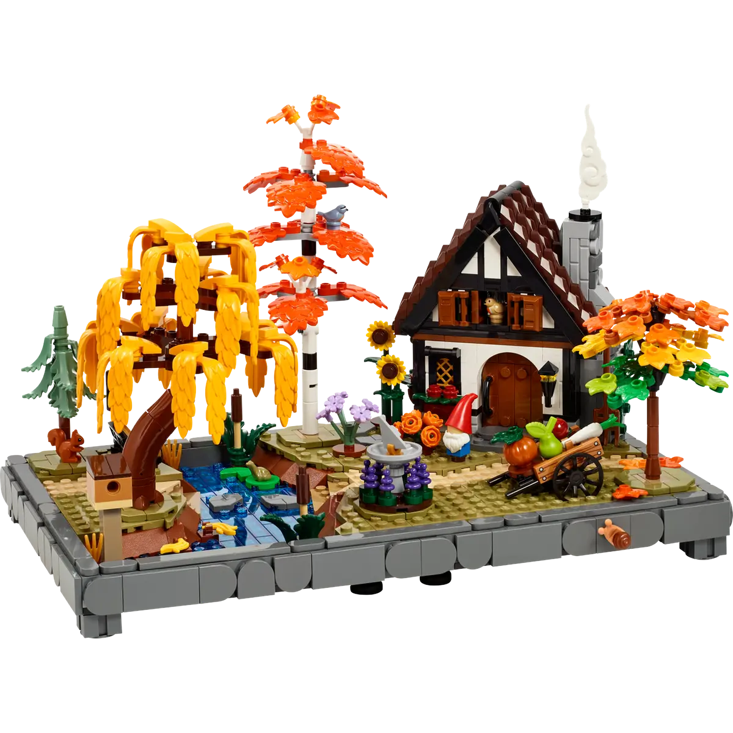 Modèle Lego d'un cottage avec jardin, étang et arbres. Une petite charrette pleine de légumes est devant le cottage.