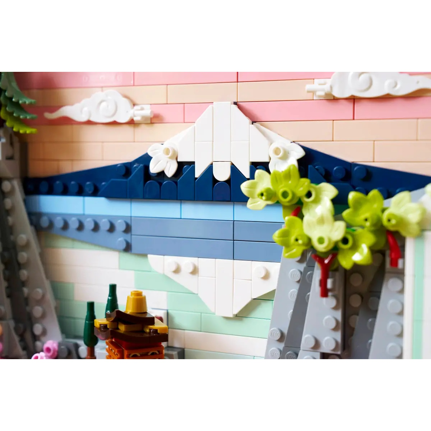 Lego scene of a mountain landscape with clouds, water and vegetation. The colors are pink, blue, white, and green.