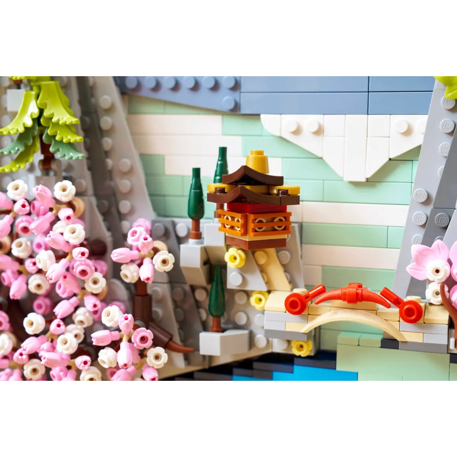 Lego scene with pink cherry blossoms, a pagoda, a bridge, and a mountain background made of Lego bricks.