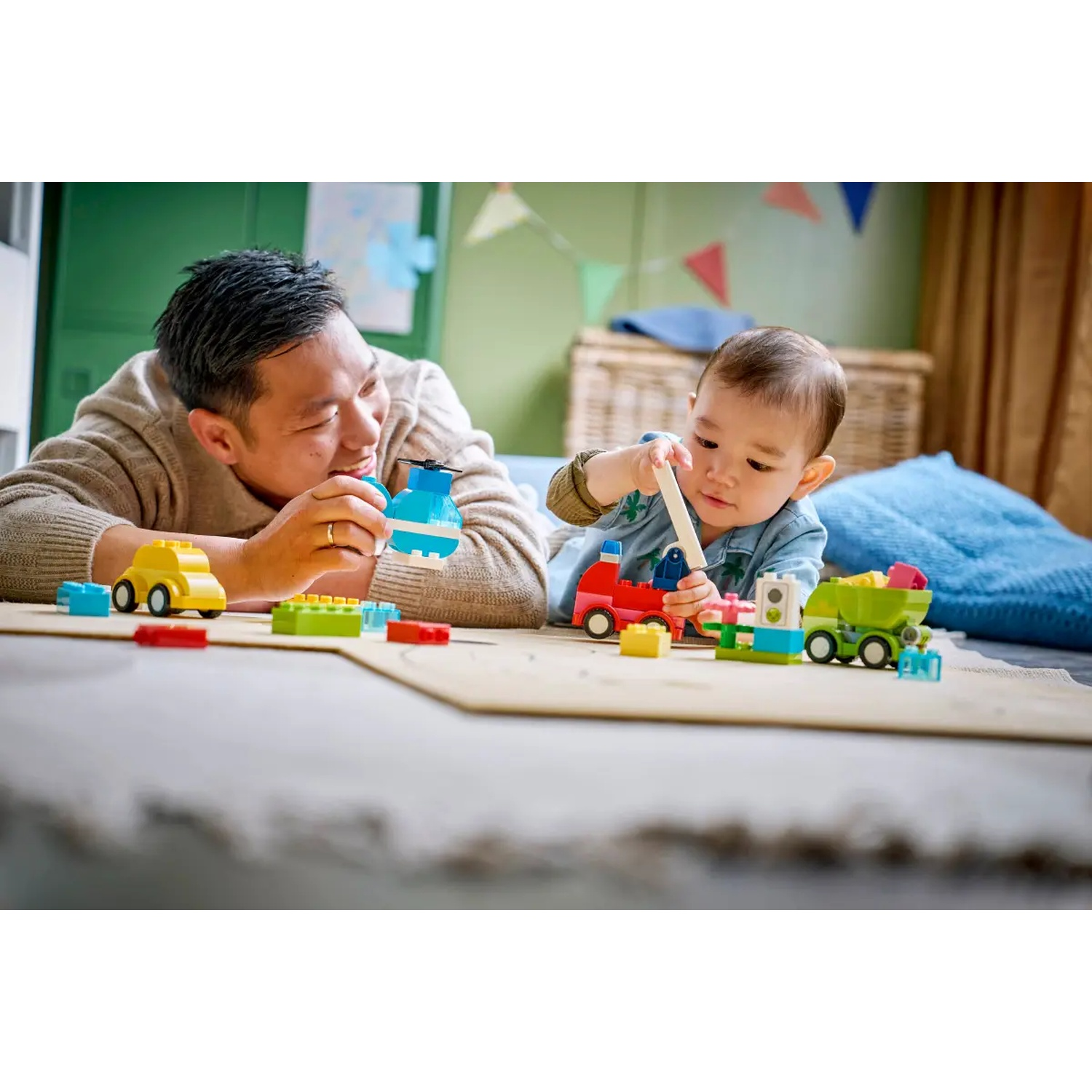Un homme et un bébé jouent avec des blocs de jouets colorés. L'homme sourit. Le bébé est concentré sur le jouet. Les jouets sont de différentes couleurs.