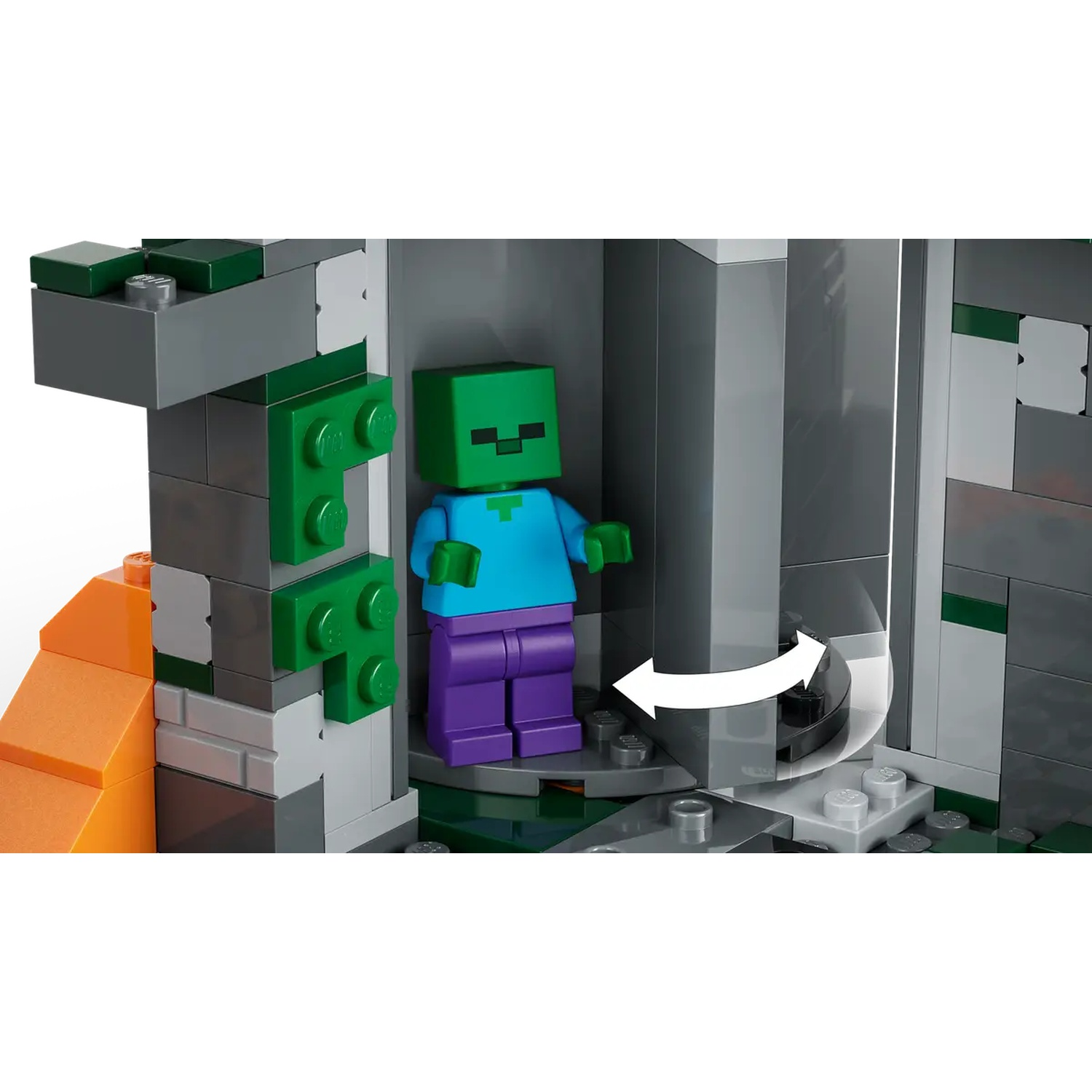 Un ensemble Lego Minecraft présente une figurine de zombie à tête verte. La scène comprend des blocs gris et verts, avec des structures orange en forme de lave.