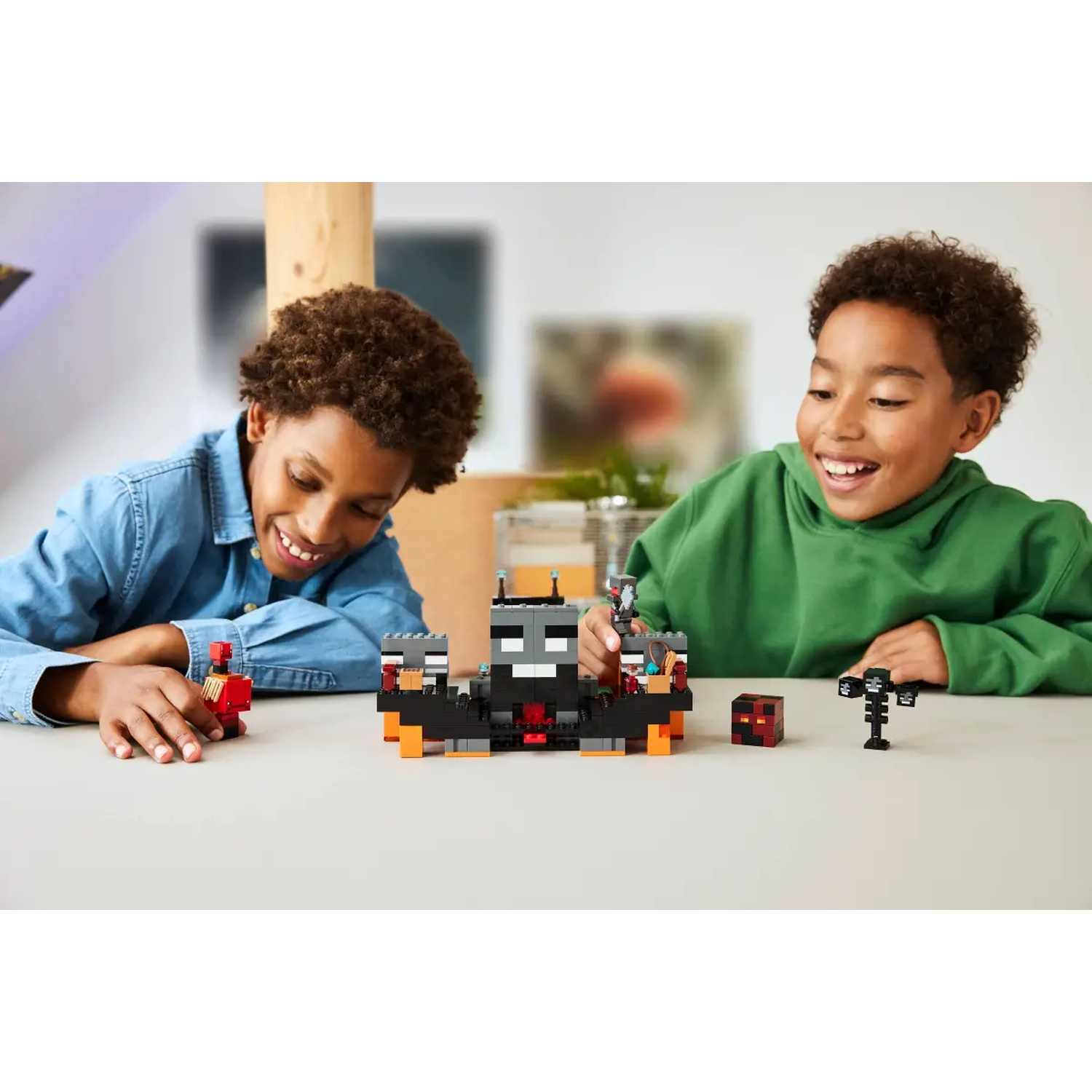 Deux garçons souriants jouent avec des ensembles Lego Minecraft. Diverses figurines et structures Lego sont sur une table blanche. L'arrière-plan est flou.
