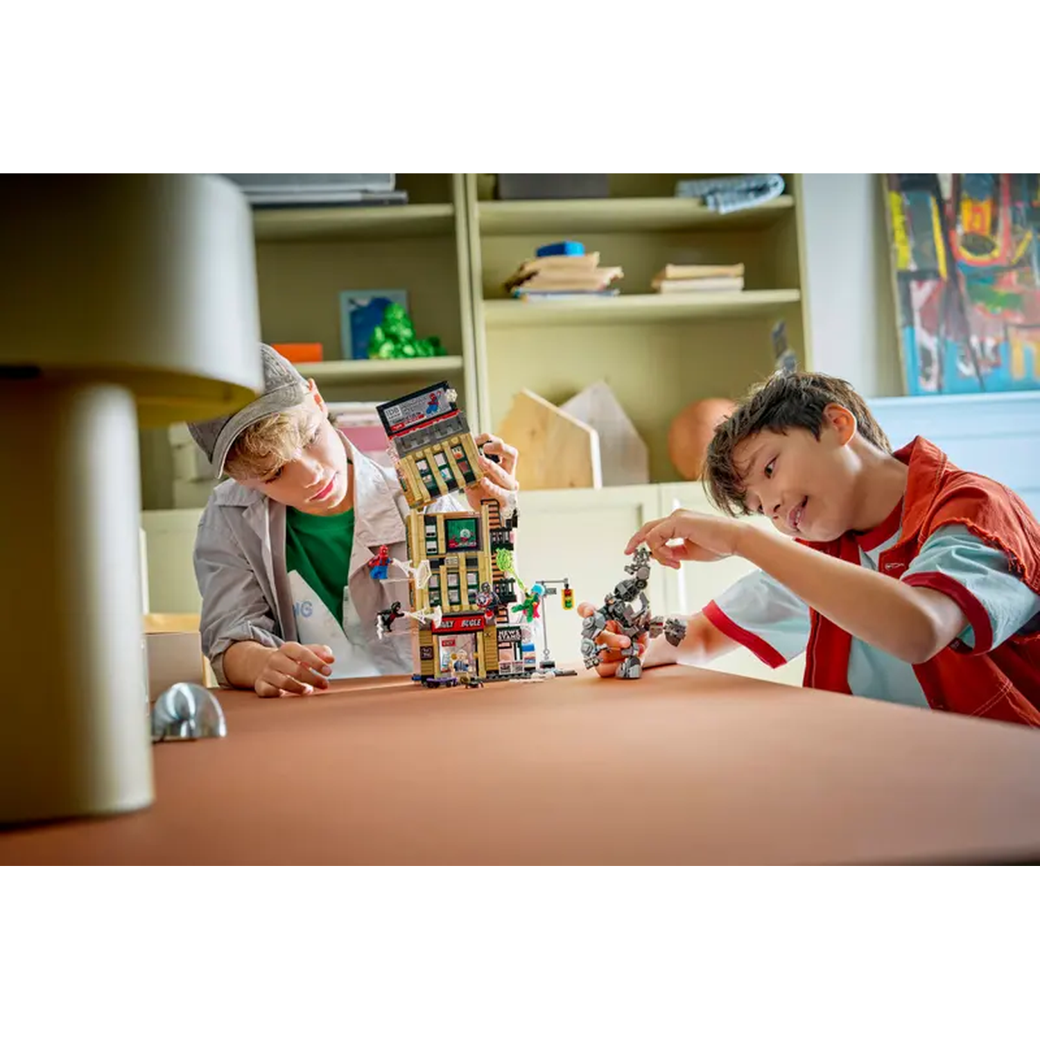 Two boys building a Lego set on a table. One boy is holding a building, the other is working on a robot.