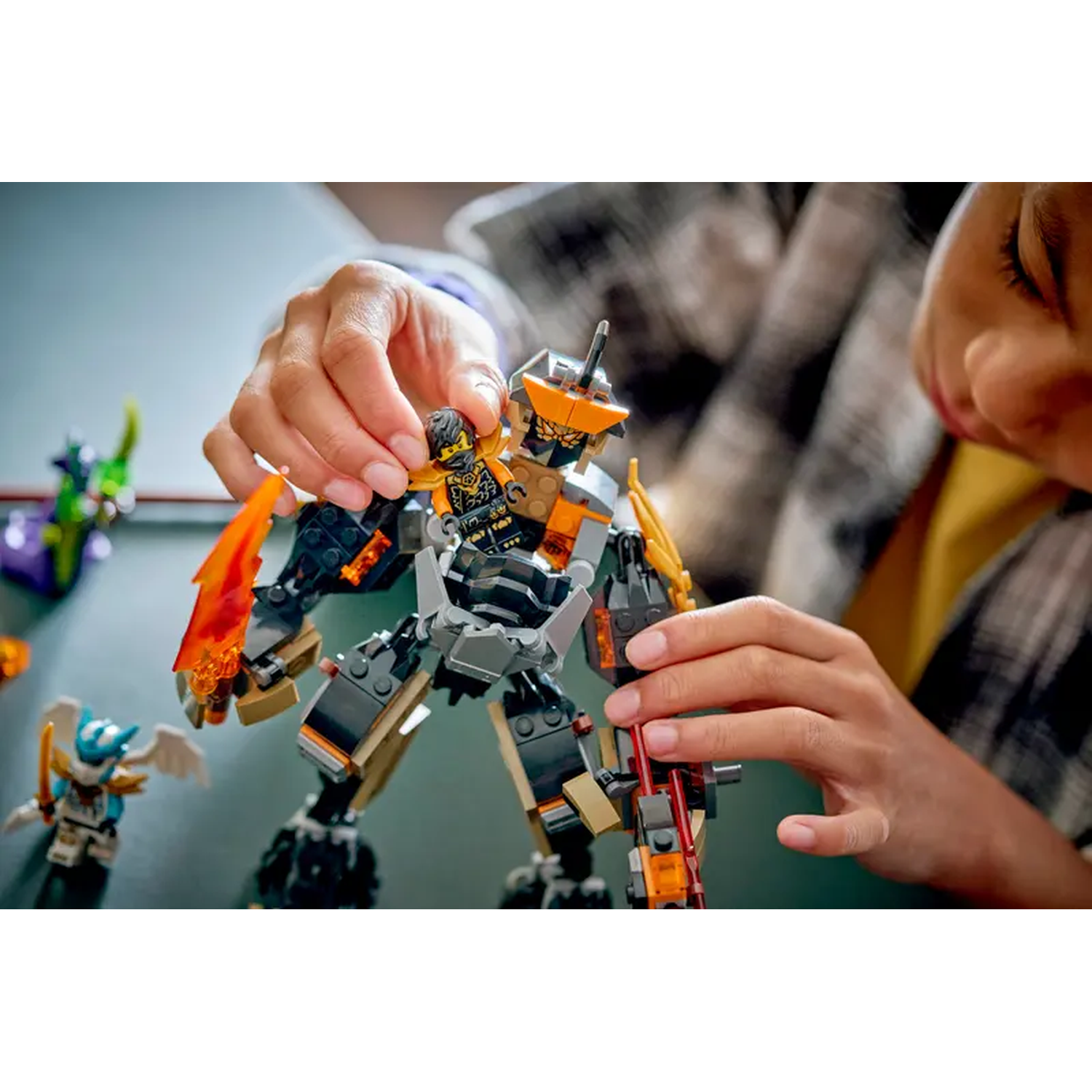 A person places a Lego figure into a Lego robot. Other Lego figures are in the background.