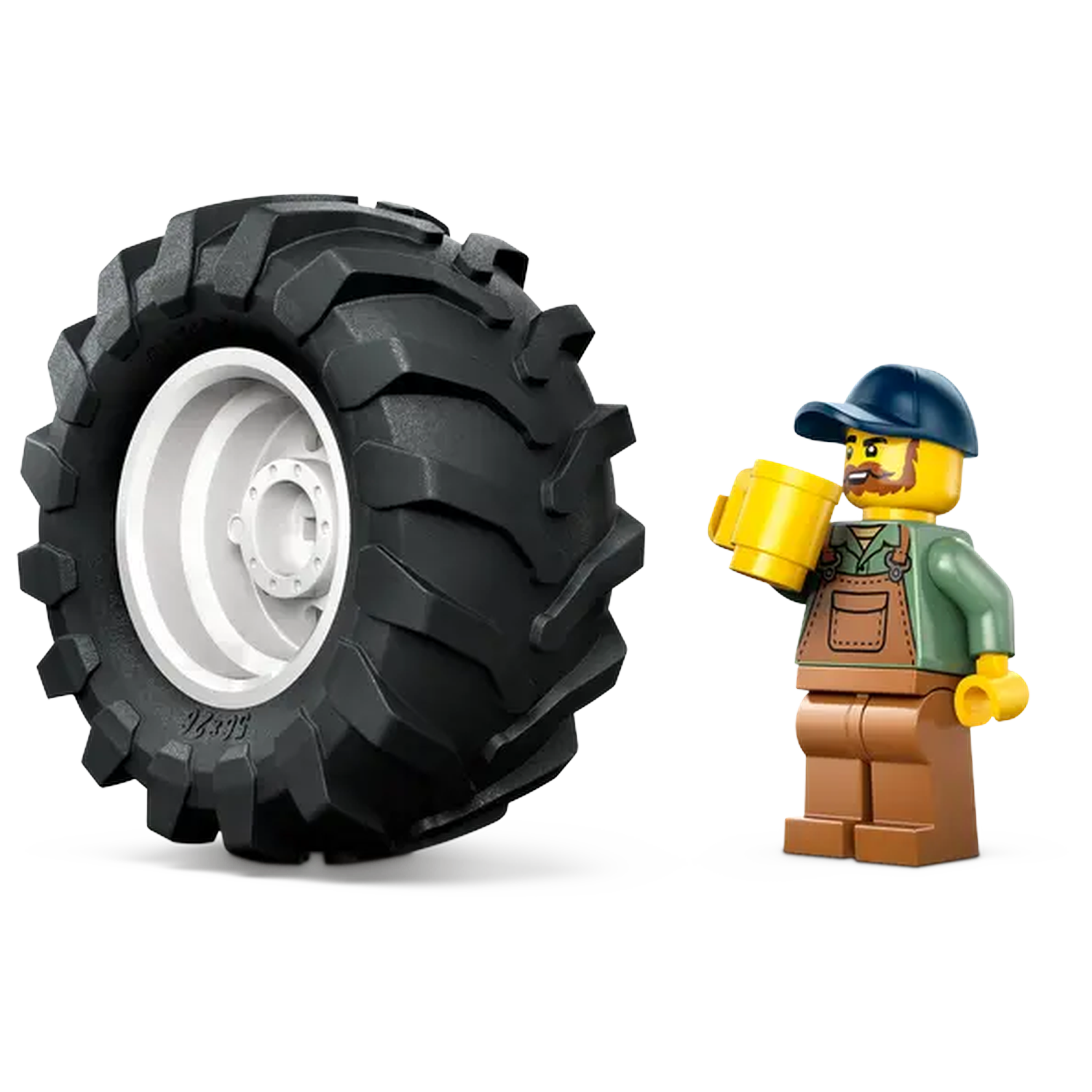 A Lego figure of a farmer holding a yellow mug stands next to a large black tractor tire with a white rim.