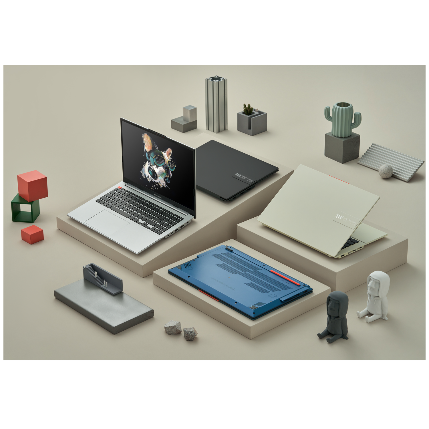 Laptops and decorative objects on platforms. A laptop screen shows a dog with glasses. Cubes and statues are also present.