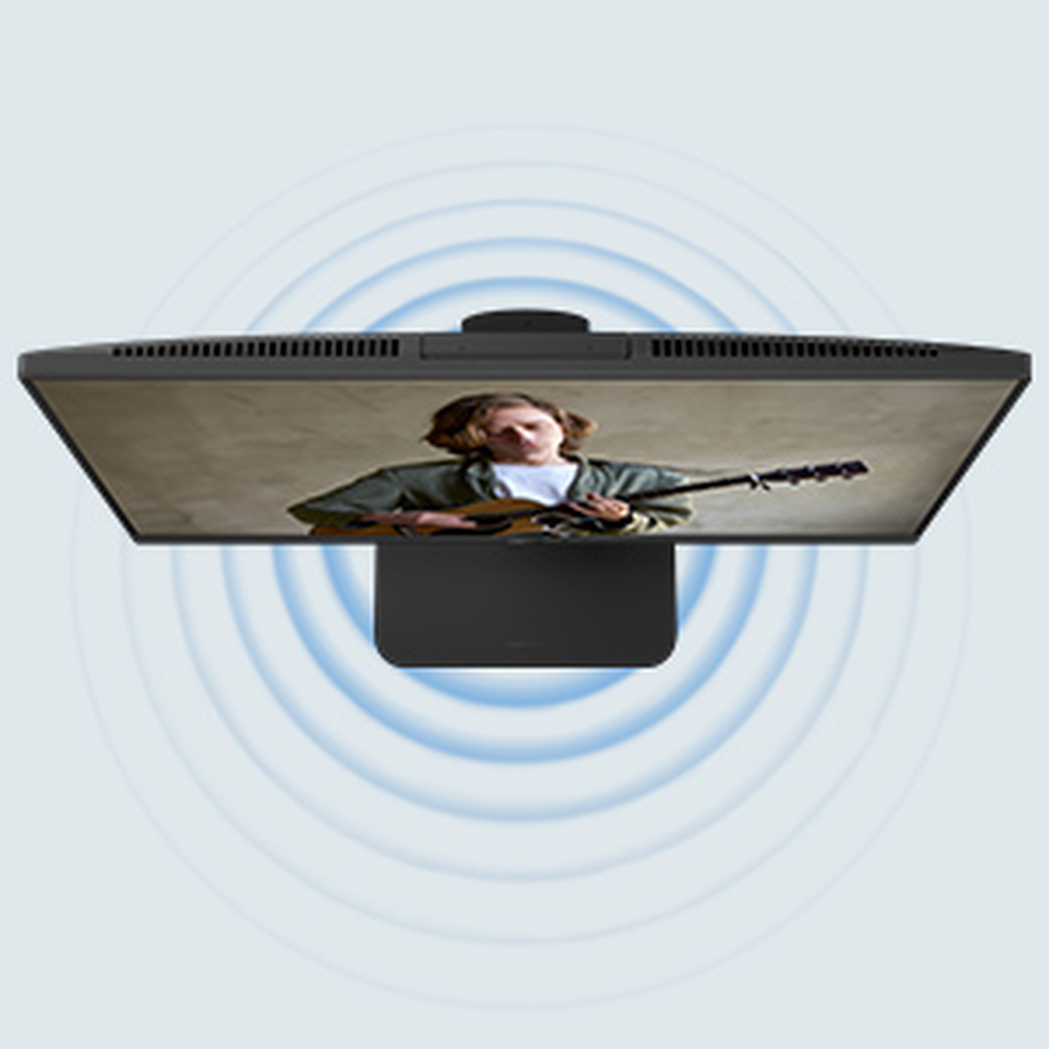 Monitor showing a person playing guitar. Blue sound wave circles surround the monitor. The monitor is black with a stand.