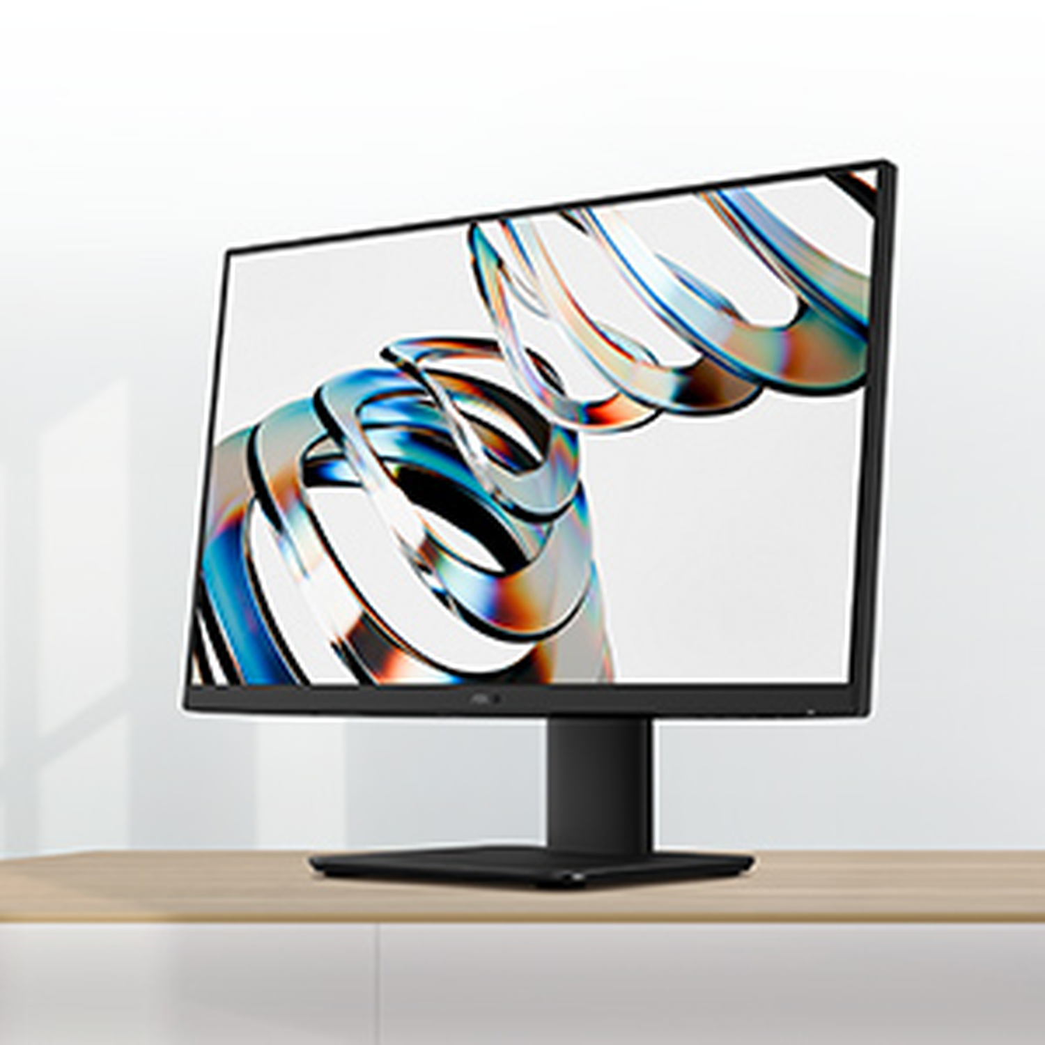 A black computer monitor displays a colorful, abstract design. It sits on a wooden desk against a white wall.