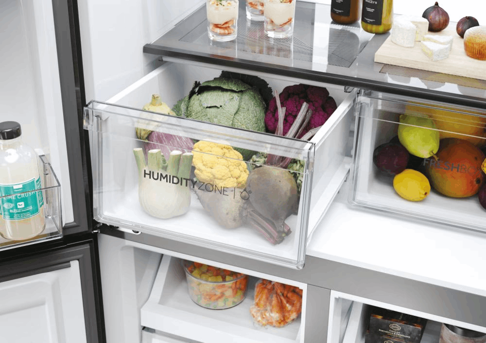 Interior del refrigerador con verduras en cajones. Se ven repollo, coliflor, remolacha e hinojo. Frascos, quesos y frutas en la parte superior.