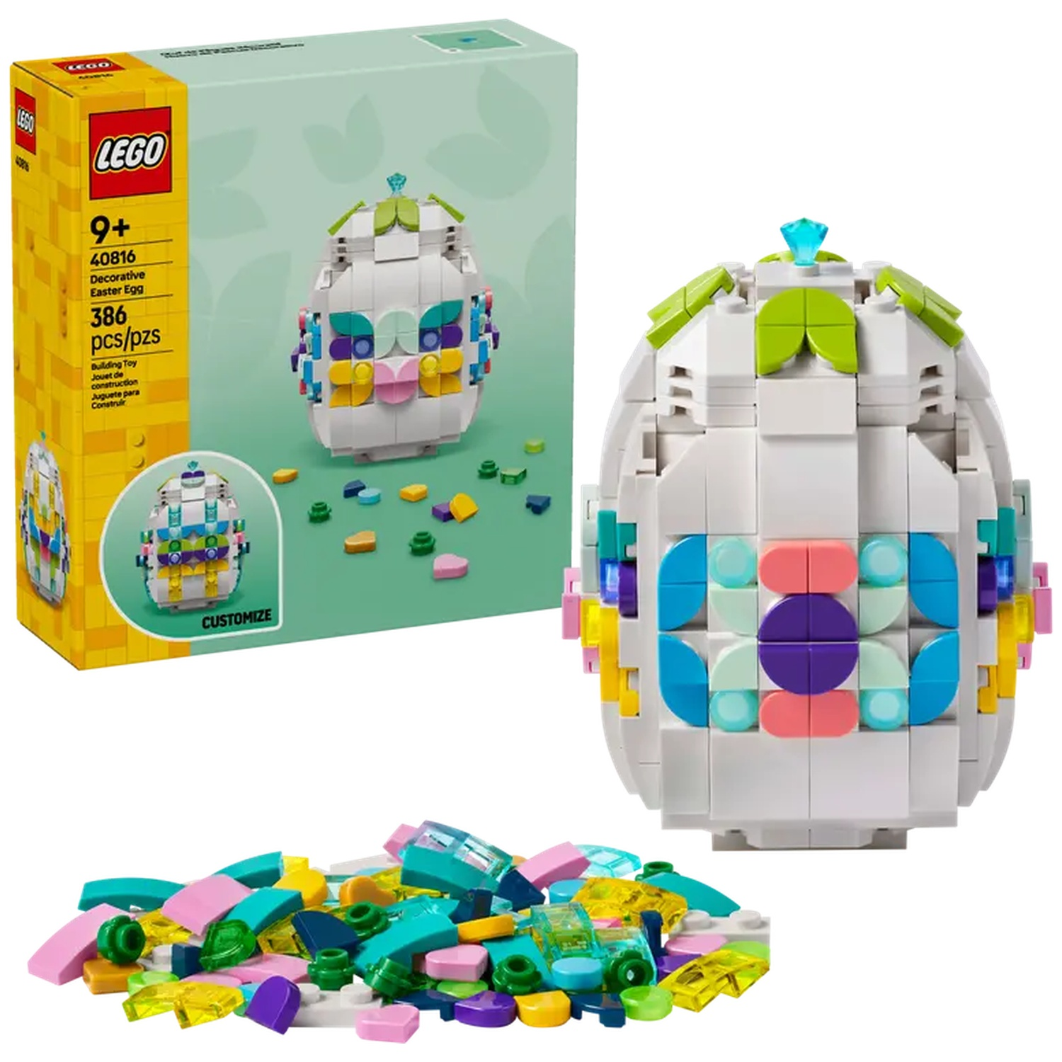 Een Lego paasei set. Het ei is wit met kleurrijke details. Een doos met de set is zichtbaar en losse stukken liggen ervoor.