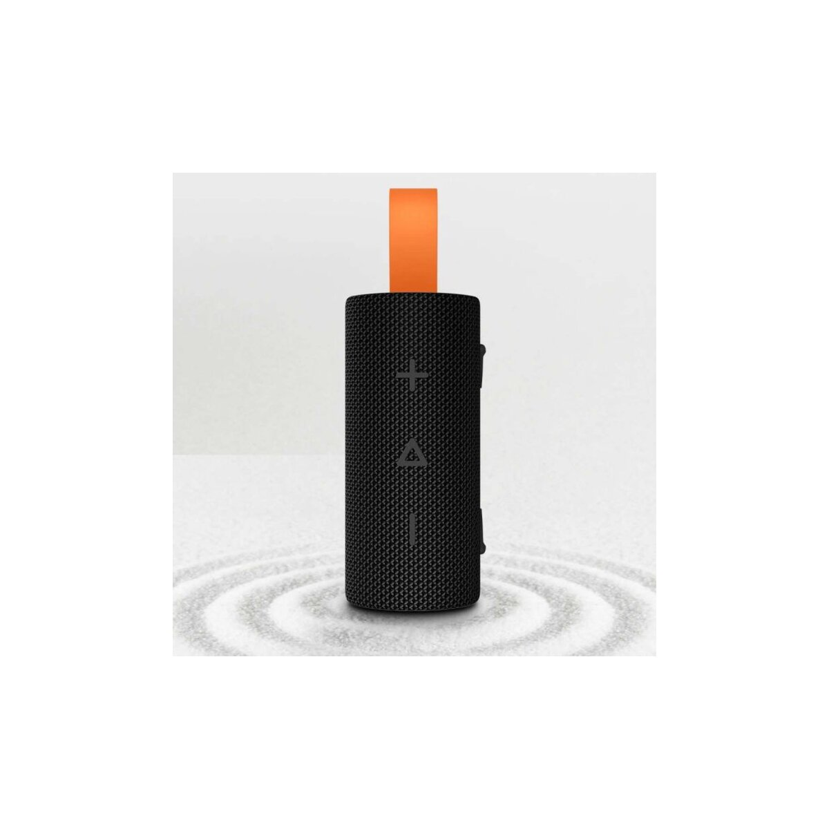 Un altavoz negro y cilíndrico con correa naranja. Se encuentra sobre una superficie con patrones de ondas.
