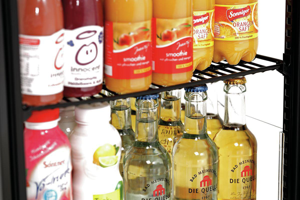 Ein Kühlschrank ist mit verschiedenen Getränken bestückt, darunter Saftflaschen und Glasflaschen mit Limonade.