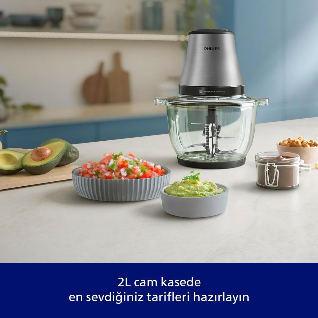 Cam kaseye sahip bir mutfak robotu, avokado, salsa, guacamole ve fındıklarla çevrili, yemek hazırlamaya hazır.