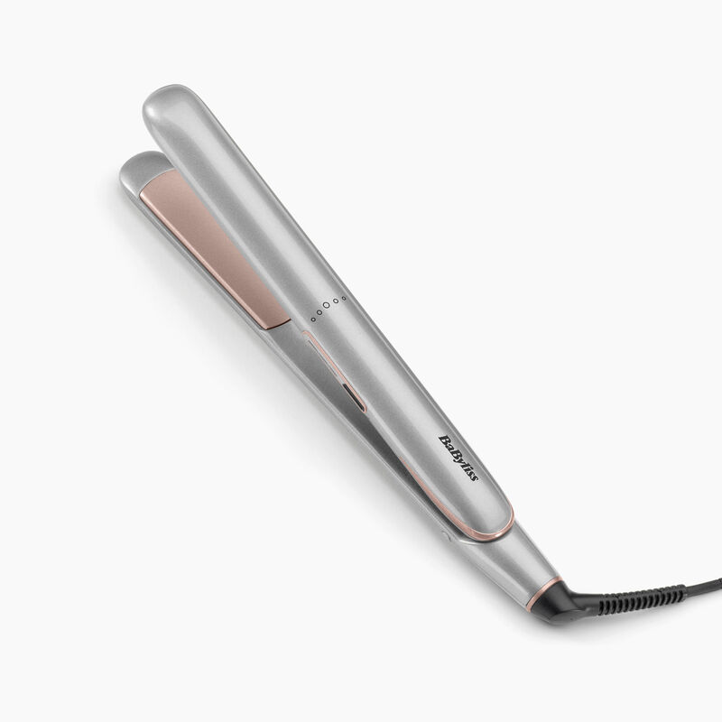 Una plancha de pelo Babyliss plateada y oro rosa. La plancha está sobre una superficie blanca, mostrando el nombre de la marca.