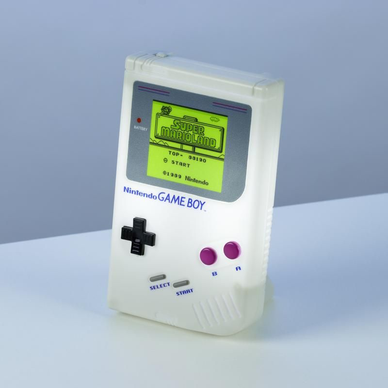 Una Game Boy blanca de Nintendo muestra Super Mario Land. Tiene una pantalla, botones y un mando direccional. El fondo es un degradado.