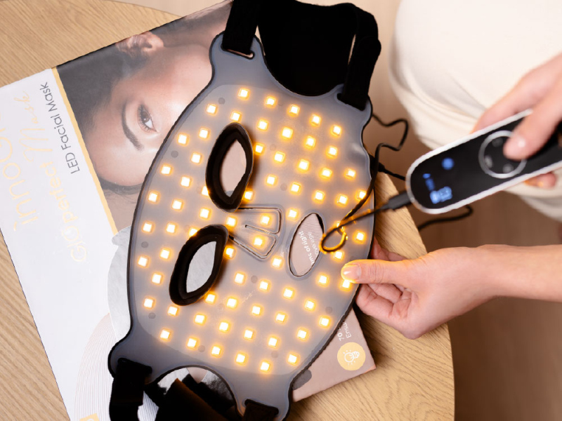 Osoba trzyma urządzenie do maski na twarz LED z kontrolerem.