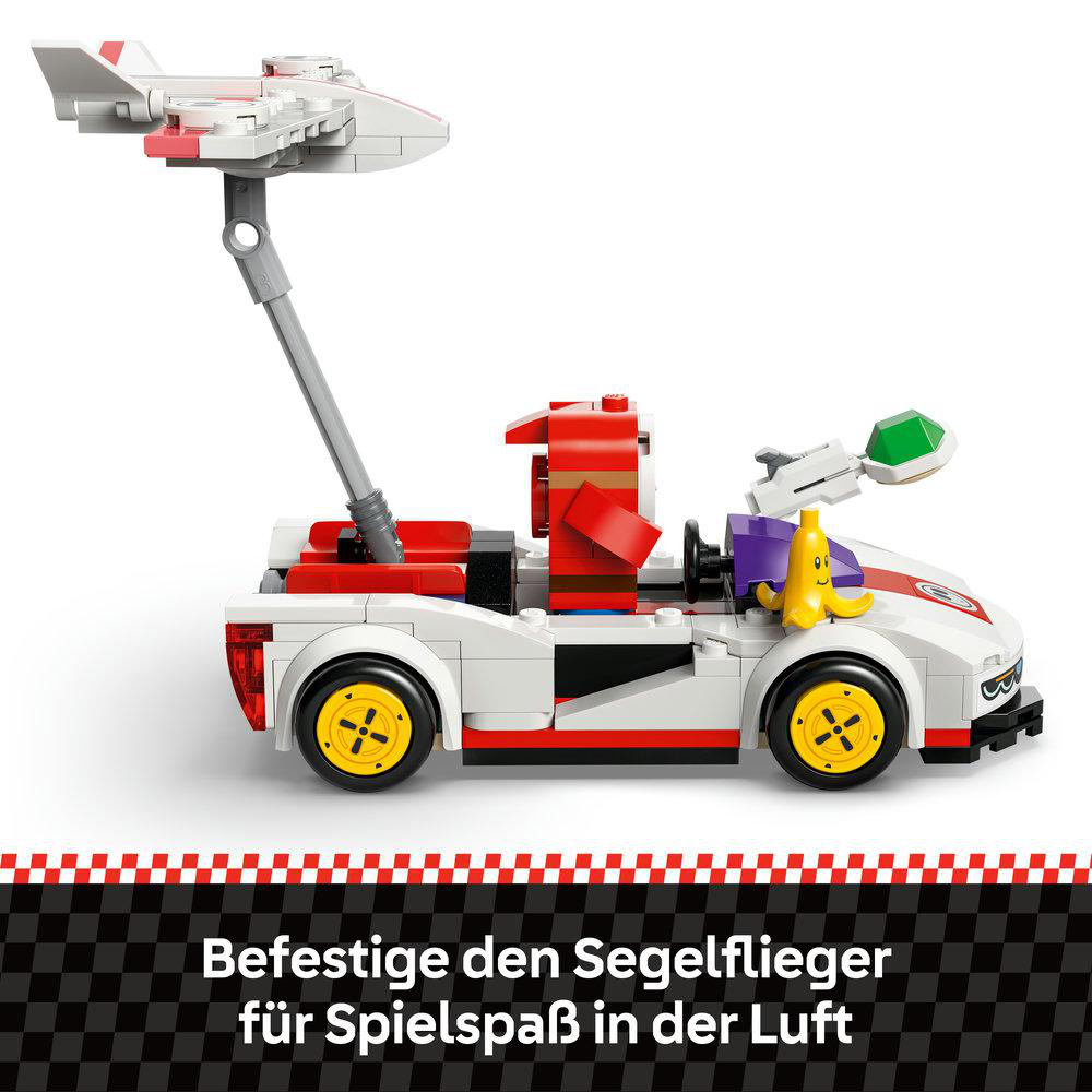 Ein weißes Spielzeugauto mit rotem Akzent und einem Flugzeug oben drauf. Eine gelbe Bananenfigur befindet sich im Auto und ein grüner Edelstein auf dem Lenkrad.