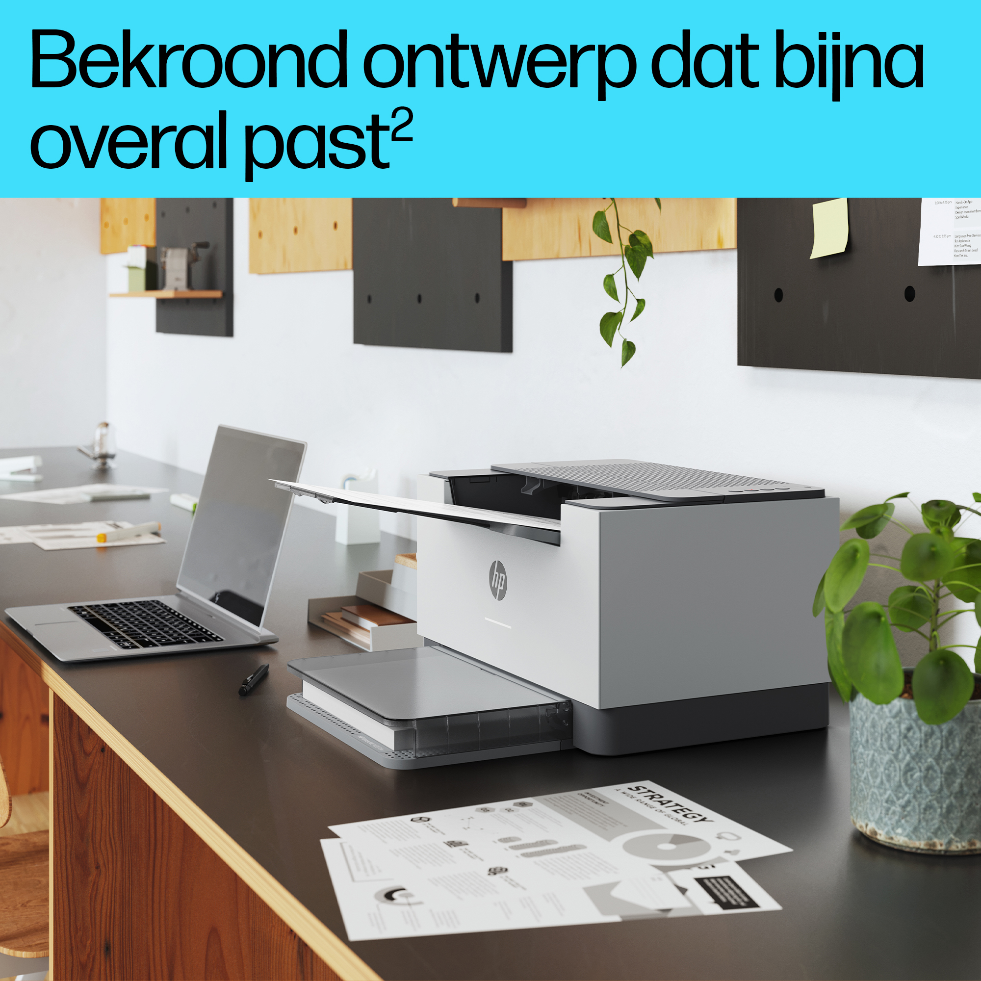 Een moderne kantooromgeving met een printer, laptop, documenten en een plant in een pot op een donker bureau.