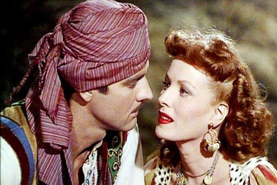 Ein Mann mit Turban und eine Frau sehen sich an. Nahaufnahme, wobei die roten Lippen der Frau und der Blick des Mannes im Fokus stehen.