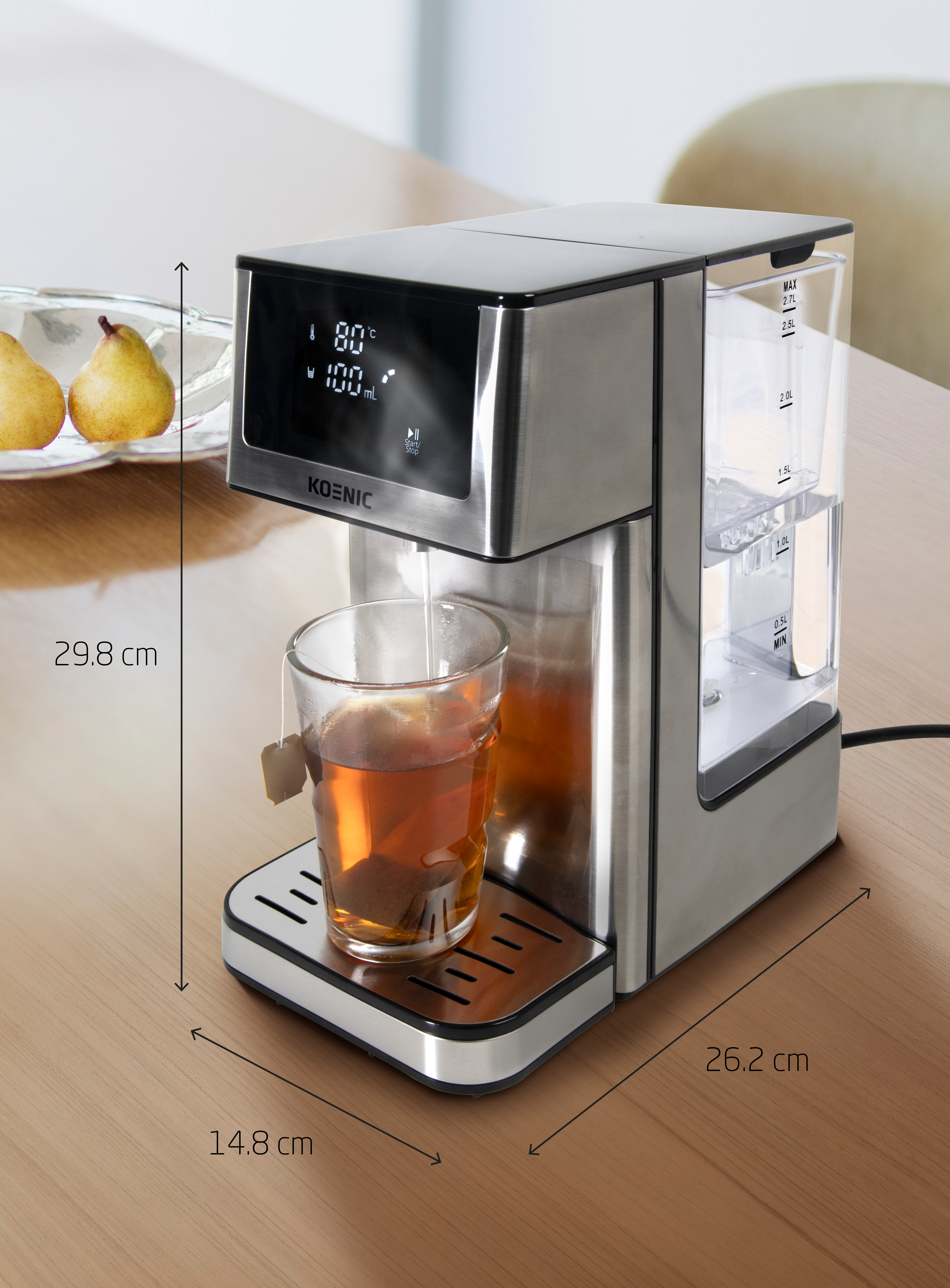 Edelstahl-Teemaschine mit einem Glas Tee. Anzeige zeigt 80°C und 100ml. Birnen im Hintergrund.