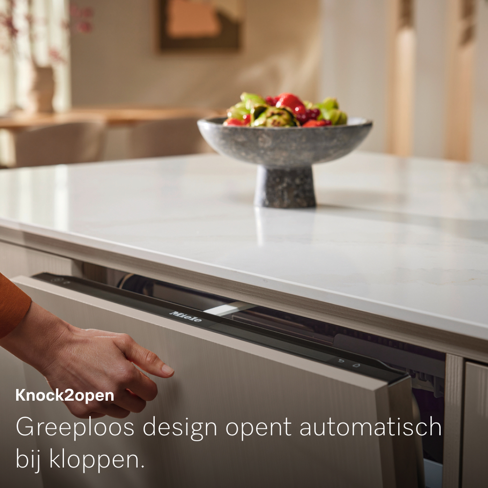 A hand opens a kitchen drawer with 'Miele' on it. A bowl of fruit sits on the countertop. Text says 'Knock2open'.