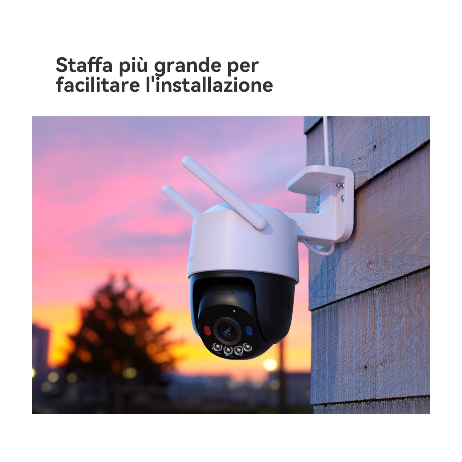 Una telecamera di sicurezza bianca e nera è montata su un muro di legno. Lo sfondo mostra un tramonto. La telecamera ha antenne.