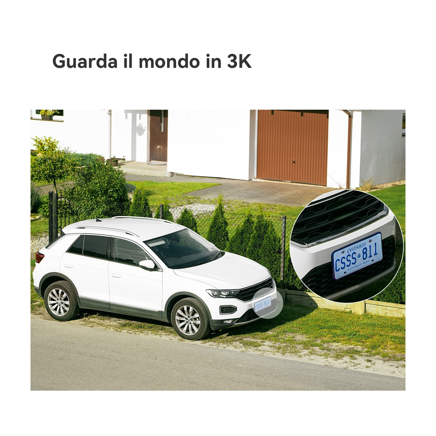 Un'auto bianca parcheggiata su una strada, con targa. Sfondo: casa, porta del garage ed erba verde.