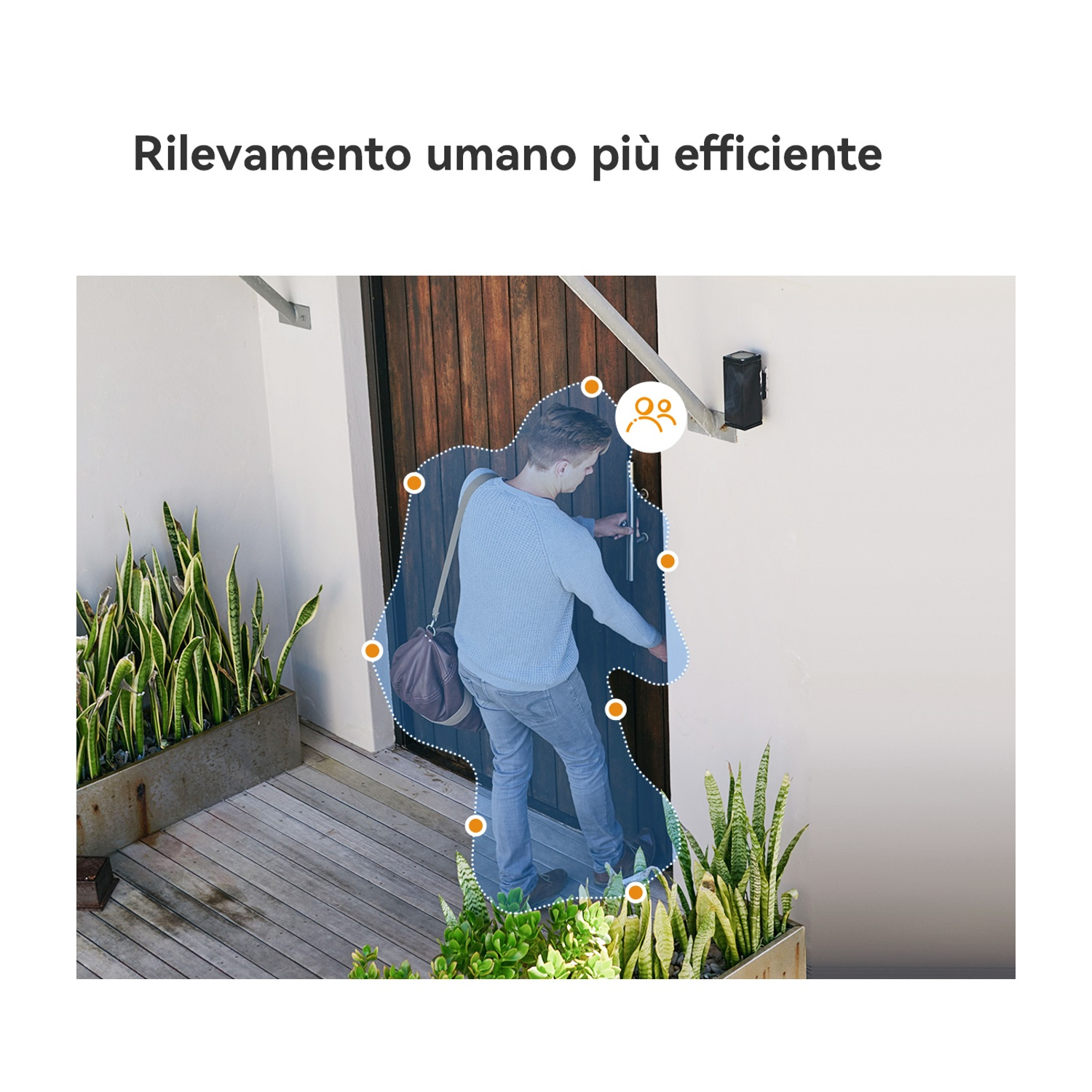 Un uomo in blu apre una porta di legno. Piante in vaso ai lati dell'ingresso. Telecamera di sicurezza sopra.