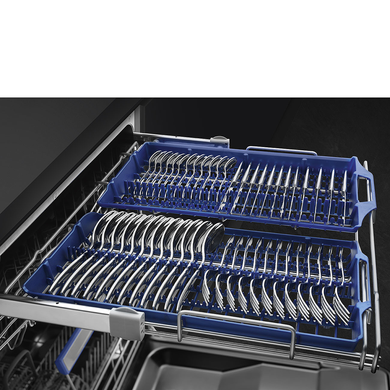 Geschirrspülerschublade mit zwei blauen Tabletts voller Besteck, Gabeln und Löffeln. Dunkler Hintergrund und Metallrahmen vorhanden.