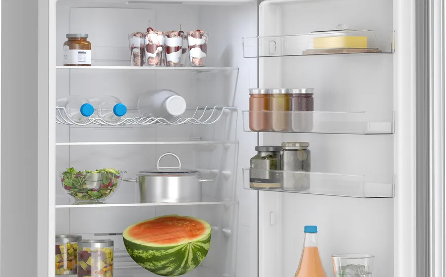 Refrigerador abierto lleno de comida: frascos, botellas de agua, ensalada, media sandía, postres y una olla.